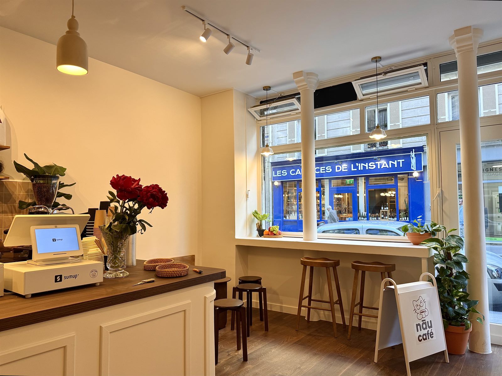 Intérieur chaleureux de NĀU CAFÉ au Marais avec comptoir blanc et bois foncé